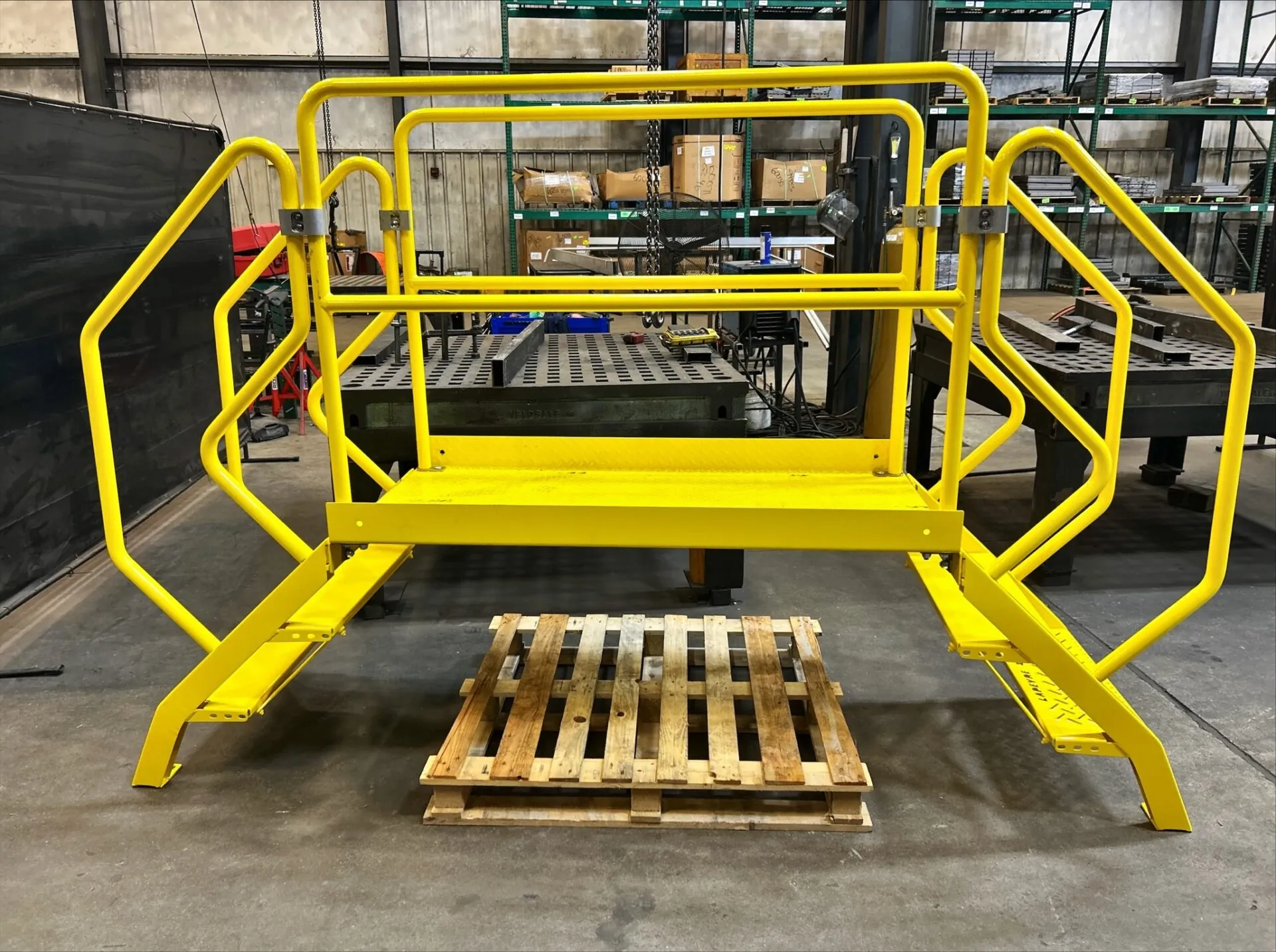 forklift is sitting in a warehouse with industrial stairs in the background